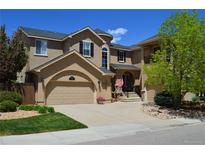 Charming two-story home with a well-manicured lawn, a two-car garage, and a welcoming entrance with an American flag at 2819 Canyon Crest Dr, Highlands Ranch, CO 80126