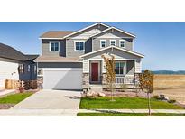Beautiful two-story home featuring a manicured lawn, attached two-car garage, and stylish architectural details at 9186 Telluride Ct, Commerce City, CO 80022