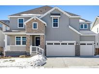 Two-story house with gray siding, stone accents, and a three-car garage at 9339 Russell Cir, Arvada, CO 80007