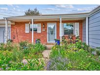 Charming brick home featuring a well-manicured front yard with vibrant flowerbeds and a welcoming porch at 9220 Lowell Blvd, Westminster, CO 80031