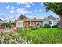 Charming brick home boasts a lush, well-manicured front yard with colorful flowerbeds and mature trees at 9220 Lowell Blvd, Westminster, CO 80031
