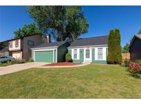 Charming green home with white trim, a well-manicured lawn, and a lovely garden at 19644 E Girard Dr, Aurora, CO 80013