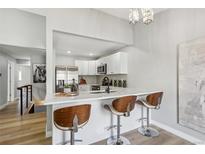 Bright modern kitchen featuring white cabinets, stainless steel appliances, and stylish bar seating at 19644 E Girard Dr, Aurora, CO 80013