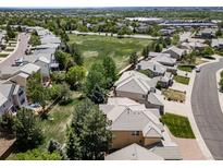 An aerial view of the homes in a residential neighborhood, a green space, and distant buildings on a sunny day at 5416 S Hannibal Ct, Centennial, CO 80015