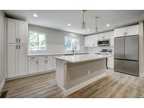 Bright kitchen features white cabinets, stainless steel appliances, and a large center island with a white countertop at 363 Lima St, Aurora, CO 80010
