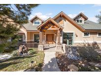 Inviting home featuring a beautiful wood porch, stone accents, and mature landscaping, creating great curb appeal at 7115 Parkwood Ln, Castle Pines, CO 80108