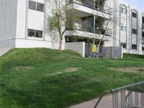 White condominium building with multiple balconies, surrounded by lush green grass at 2325 S Linden Ct # 101, Denver, CO 80222