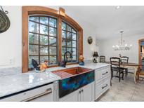 Bright kitchen with a copper sink, white marble countertops, white cabinetry, and a view of the outdoors at 689 Red Deer Rd, Franktown, CO 80116