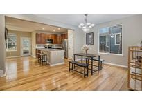 Open dining room with hardwood floors adjacent to the kitchen, featuring a modern chandelier and natural light at 10247 Telluride Way, Commerce City, CO 80022