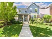 Charming blue two-story home featuring a inviting front porch and well-manicured landscaping at 7860 E Ellsworth Ave, Denver, CO 80230