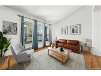 Bright living room with a leather sofa, area rug, and plenty of natural light from the large windows at 2730 River View Dr, Broomfield, CO 80023
