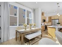 Bright dining area with a wooden table, stylish bench, large windows, and seamless flow into the modern kitchen at 2855 S Pancratia St, Denver, CO 80236