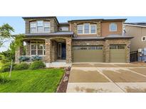 Two-story home featuring a stone and siding exterior, a well-manicured lawn, and a two-car garage at 1648 Exquisite St, Castle Rock, CO 80109