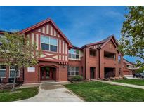 Charming condo building featuring Tudor style architecture with brick and decorative trim, lush lawn, and mature tree at 1379 Charles # 4, Longmont, CO 80503