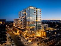 Stunning exterior view of a modern high-rise building with large windows and city lights at twilight at 4200 W 17Th Ave # 323, Denver, CO 80204