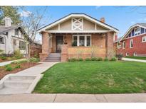 Charming brick home featuring a covered front porch, well-maintained lawn, and beautiful architectural details at 916 Adams St, Denver, CO 80206