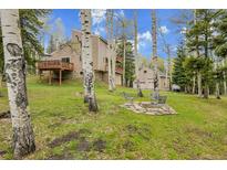 Landscaped backyard features a fire pit area, a house with decks, and surrounding Aspen trees at 2654 Sinton Rd, Evergreen, CO 80439