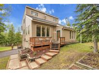 Charming home with tiered deck, landscaped yard and natural light, nestled in a wooded setting against a blue sky at 2654 Sinton Rd, Evergreen, CO 80439