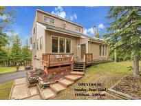 Inviting two-story home featuring a wooden deck, steps, and landscaped yard with mature trees at 2654 Sinton Rd, Evergreen, CO 80439