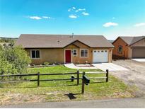 Charming single-story home with a red door, landscaped front yard, and attached garage at 749 Westward Ln, Palmer Lake, CO 80133