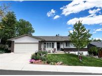 Charming single-story home with a manicured lawn, beautiful landscaping, and a cozy front porch seating area at 12739 W Alabama Pl, Lakewood, CO 80228