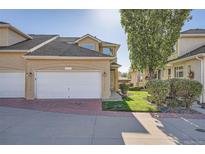 Charming stucco home boasts an attached two-car garage and manicured lawn at 2417 S Racine Way, Aurora, CO 80014