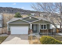 Green house with white garage door and landscaping at 7139 Pine Hills Way, Littleton, CO 80125