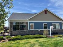 Charming home exterior showcasing a stone facade, blue siding, and a well-manicured lawn at 12604 Madison Way, Thornton, CO 80241