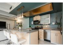 Modern kitchen features stainless steel appliances, a breakfast bar, and stylish pendant lighting at 675 S University Blvd # 106, Denver, CO 80209