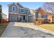 Charming two-story home with gray exterior, brick accents, and a spacious driveway at 11545 S Flower Mound Way, Parker, CO 80134