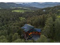Stunning aerial view of a home nestled in a forest with mountain views and solar panels at 91 Hess Ave, Golden, CO 80401