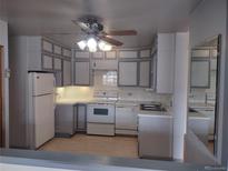 Traditional kitchen with white appliances, neutral countertops, ample cabinetry and unique ceiling fan at 680 S Alton Way # 9A, Denver, CO 80247