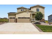 Tan two story home featuring a 3-car garage, stone accents, and well-manicured landscaping at 42830 Ivydel St, Elizabeth, CO 80107