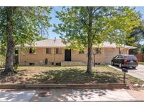 Charming single-story home with brick facade, complemented by mature trees and a well-maintained front yard at 140 S Kendall St, Lakewood, CO 80226