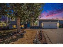 Charming home featuring a blue exterior and a mature tree in the front yard and a blue door at 6532 S Field Way, Littleton, CO 80123