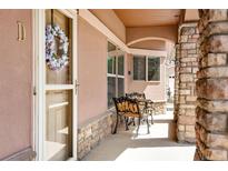 Inviting front porch with cozy seating, stone accents, and a decorative wreath on the door at 15501 E 112Th Ave # 33D, Commerce City, CO 80022
