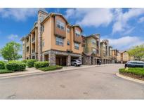 Apartment building exterior with a stone facade, garage parking and well-maintained landscaping at 15460 Canyon Gulch Ln # 105, Englewood, CO 80112