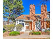 Charming townhome featuring a brick chimney, cozy front porch, and well-manicured landscaping at 2862 W Long Dr # A, Littleton, CO 80120