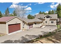 Home exterior featuring a three car garage, large driveway and basketball hoop at 24 Navajo Trl, Evergreen, CO 80439