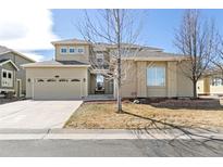 Tan two-story home with a two-car garage and a well-maintained lawn on a sunny day at 6690 S Fenton St, Littleton, CO 80123