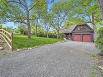 Charming home with a gravel driveway, lush lawn, and mature trees at 845 Urban St, Lakewood, CO 80401