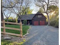 Charming home with red garage doors and a gravel driveway, surrounded by mature trees at 845 Urban St, Lakewood, CO 80401