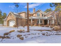 Stunning two-story home with stone and stucco accents, a three-car garage, and a partially snow-covered yard at 17820 Queensmere Dr, Monument, CO 80132