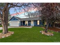 Charming blue home featuring a well-manicured lawn, and a cozy front porch with decorative trees at 20908 E Dorado Cir, Centennial, CO 80015