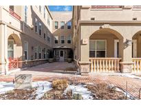 Exterior of a tan home with brick courtyard, covered entrances and manicured landscaping at 40 Madison St # 103, Denver, CO 80206