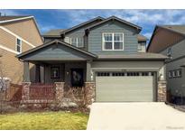 Charming two-story home featuring a covered porch, two-car garage, and manicured front lawn at 476 Hyde Park Cir, Castle Pines, CO 80108
