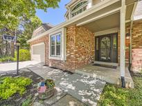 Charming brick home featuring a covered front entrance and manicured landscaping at 7782 S Louthan St, Littleton, CO 80120