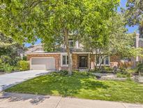 Charming brick home featuring mature landscaping, a two-car garage, basketball hoop, and a classic, welcoming facade at 7782 S Louthan St, Littleton, CO 80120
