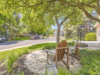 Relaxing front yard featuring Adirondack chairs, a small table, and shade trees, creating a welcoming curb appeal at 7782 S Louthan St, Littleton, CO 80120