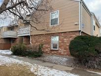 A two-story condo with brick and tan siding, complemented by lush bushes at 3328 S Ammons St # 4-104, Lakewood, CO 80227